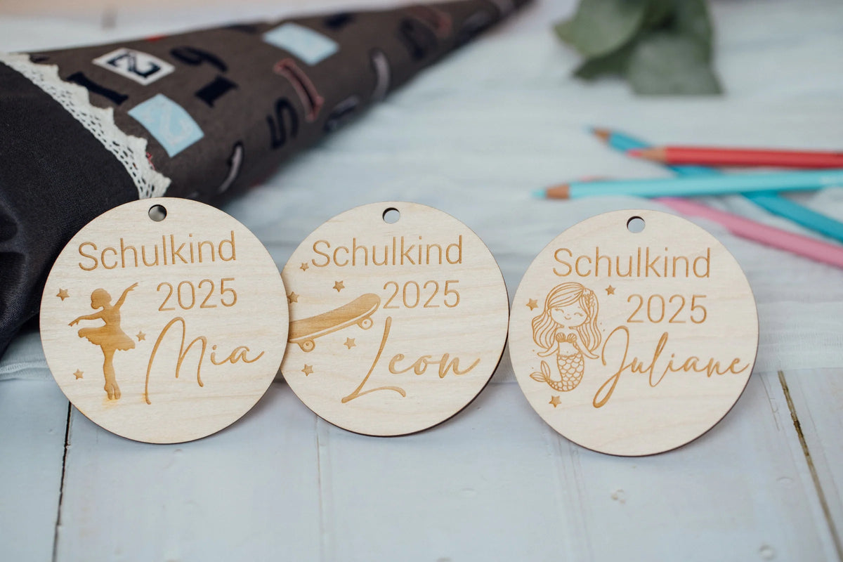 Drei Schultütenanhänger aus Holz mit Namen vor einer Schultüte