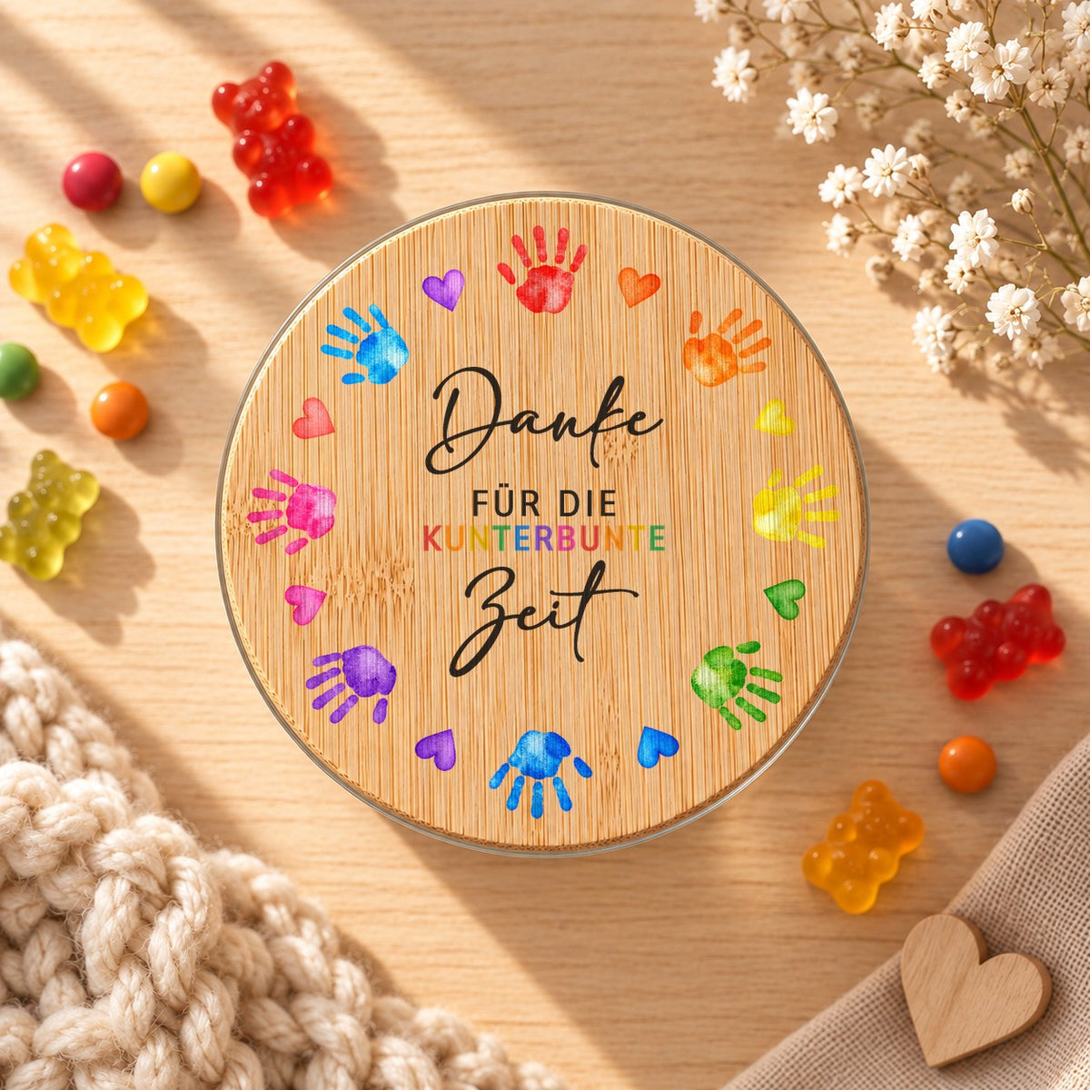 Vorratsglas „Danke für die kunterbunte Zeit“ als Geschenk für die Erzieherin, Design Kinderhände: Bambusdeckel von oben, daneben Gummibärchen