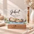 Geldgeschenk zur Geburt als Acryl-Aufsteller im Otter-Design: Otter-Mama mit Baby, Röhrchen mit Geldschein