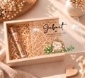 Geldgeschenk zur Geburt in Holzkiste im Igel-Design, Deckel halb offen, Reagenzglas mit Geldschein in Holzwolle