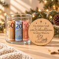 Geldgeschenk Weihnachten im Glas: offenes Glas mit gerollten Geldscheinen, daneben lehnt der gravierte Bambusdeckel „Gruß vom Weihnachtsmann“