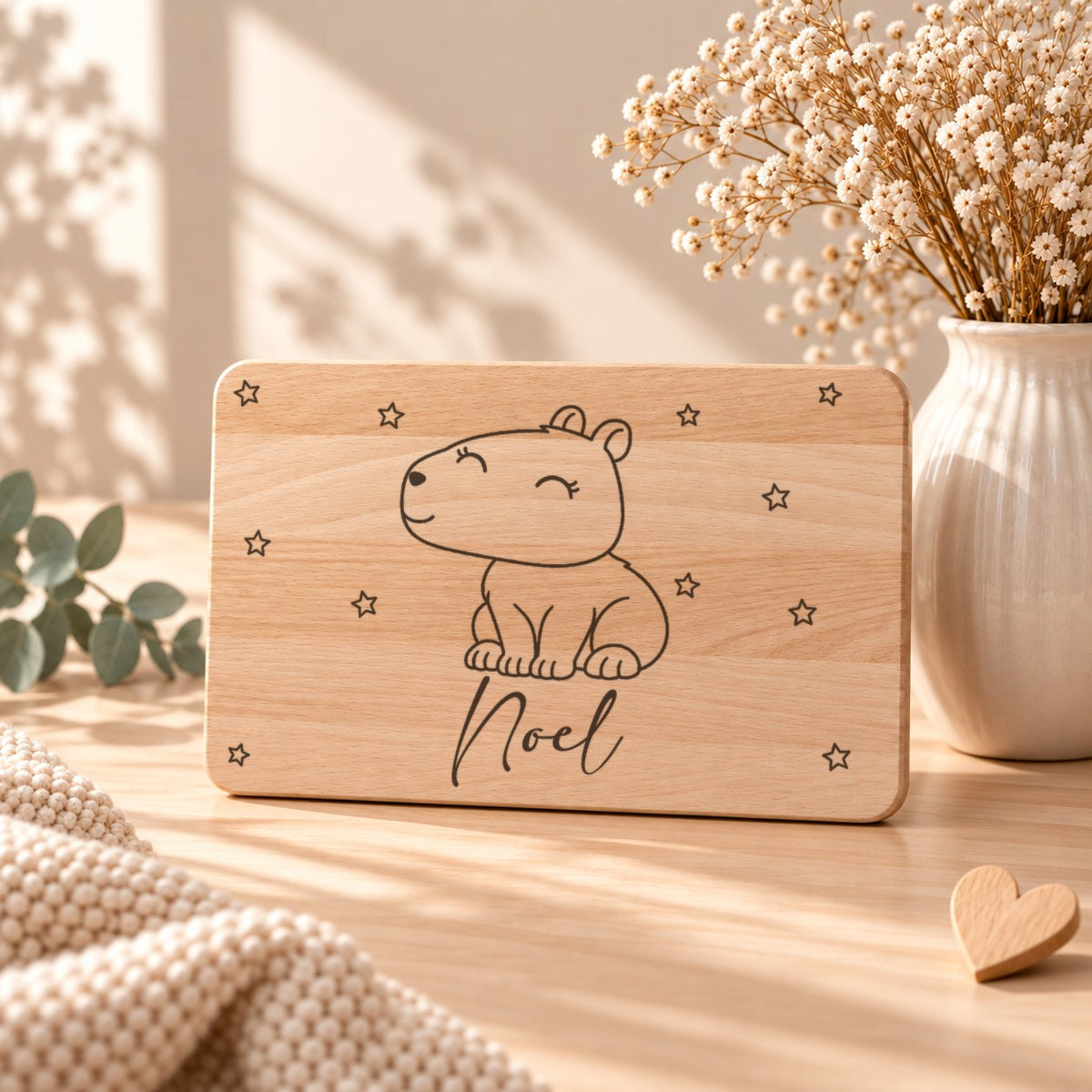 Frühstücksbrettchen aus Holz mit einem Capybara, aufgestellt neben Schleierkraut