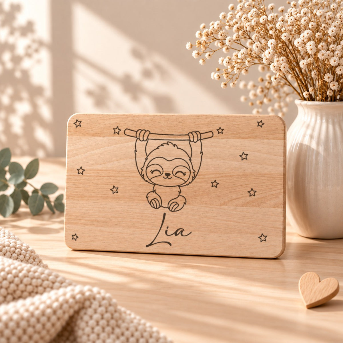Frühstücksbrettchen aus Holz mit einem Faultier, aufgestellt neben Schleierkraut
