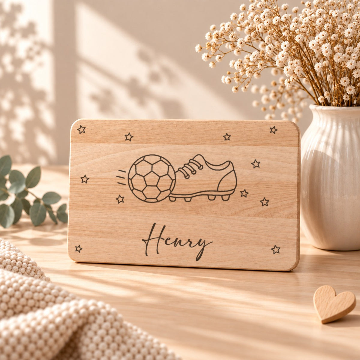 Frühstücksbrettchen aus Holz mit einem Fußball, aufgestellt neben Schleierkraut