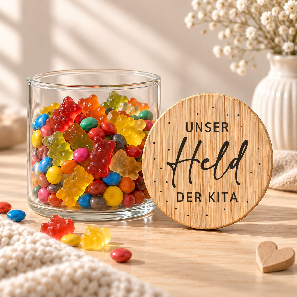 Offenes Vorratsglas mit Gummibärchen, daneben lehnt der Deckel „Unser Held der Kita“
