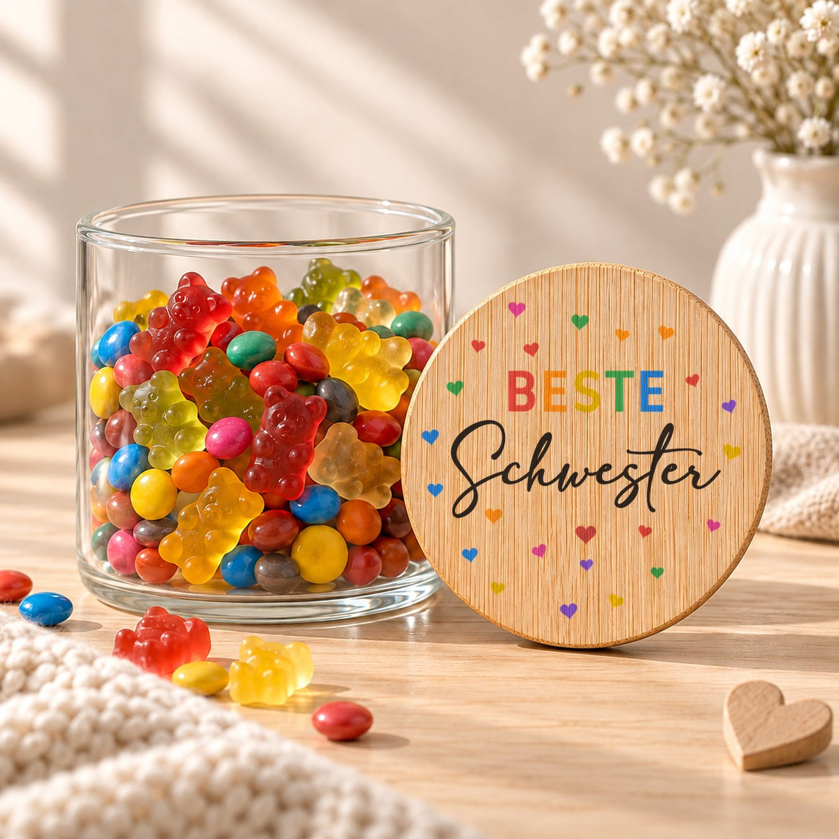 Offenes Vorratsglas mit Gummibärchen, daneben lehnt der Deckel „Beste Schwester“