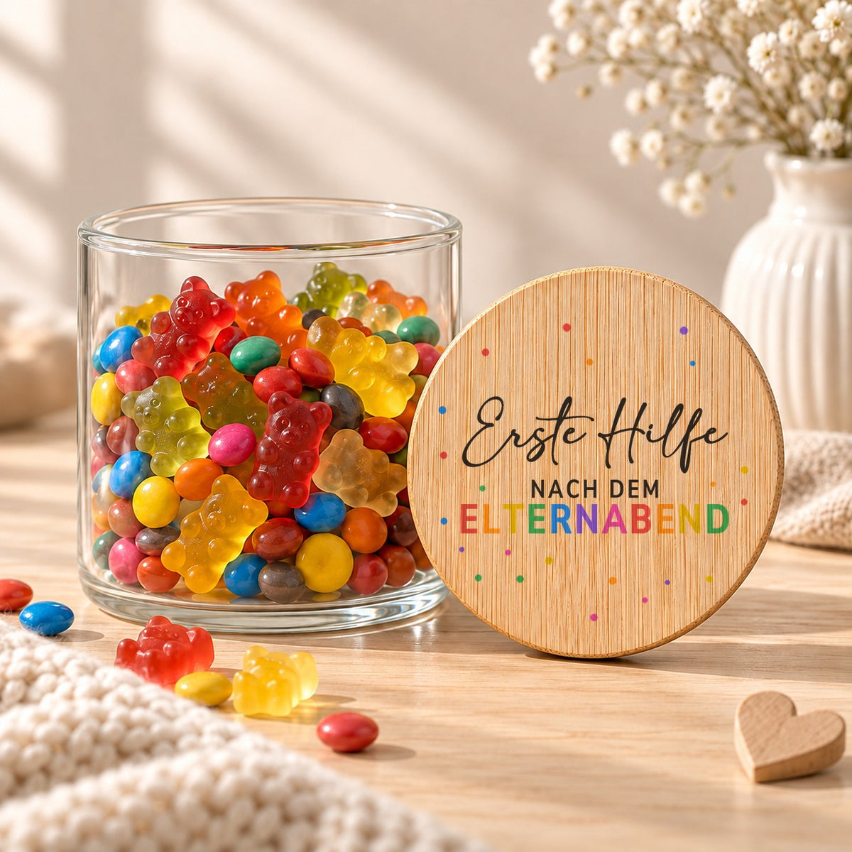 Offenes Vorratsglas mit Gummibärchen, daneben lehnt der Deckel „Erste Hilfe nach dem Elternabend“