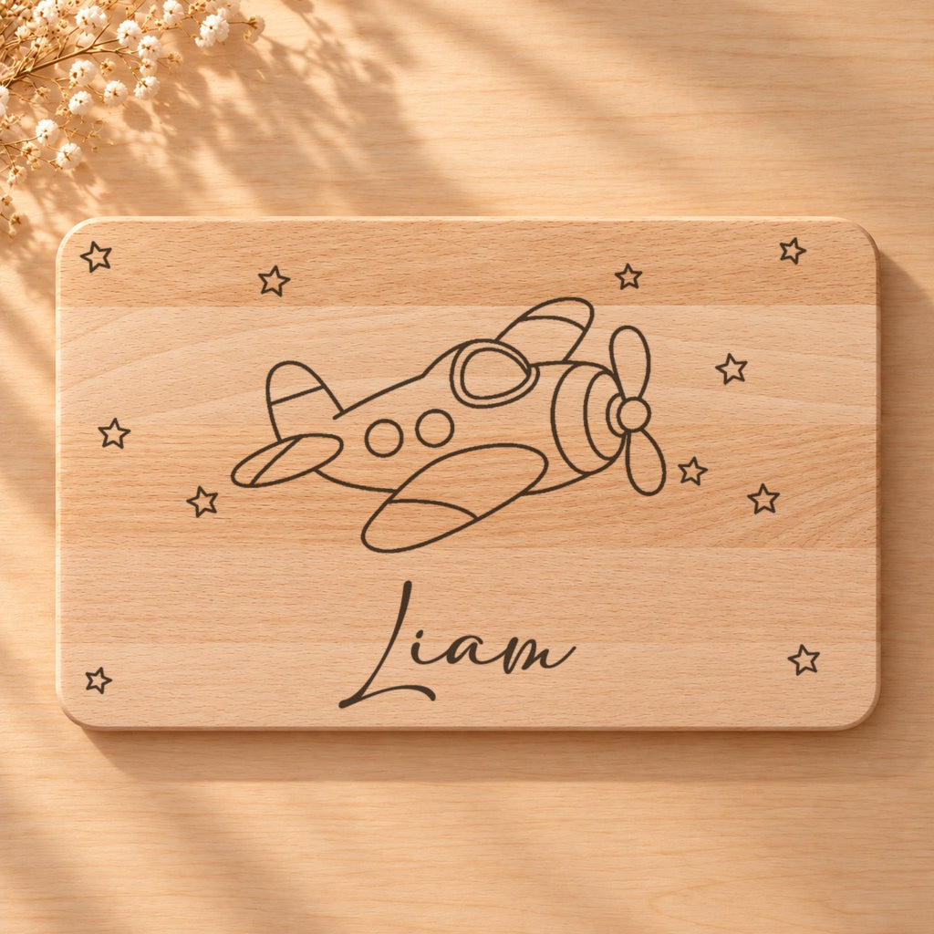 Nahaufnahme der Lasergravur: Flugzeug und der Name Liam in Schreibschrift auf hellem Holz