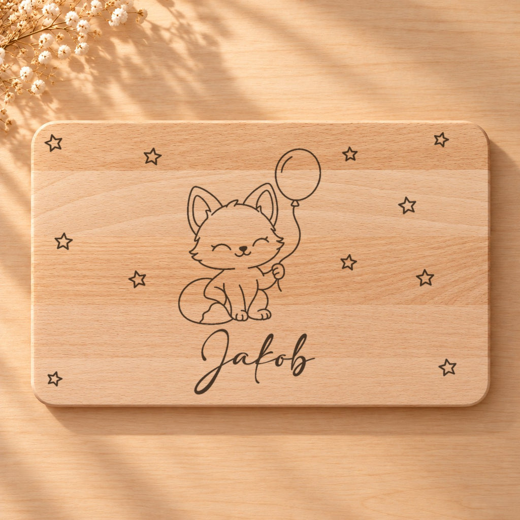 Nahaufnahme der Lasergravur: Fuchs mit Luftballon und der Name Jakob in Schreibschrift auf hellem Holz