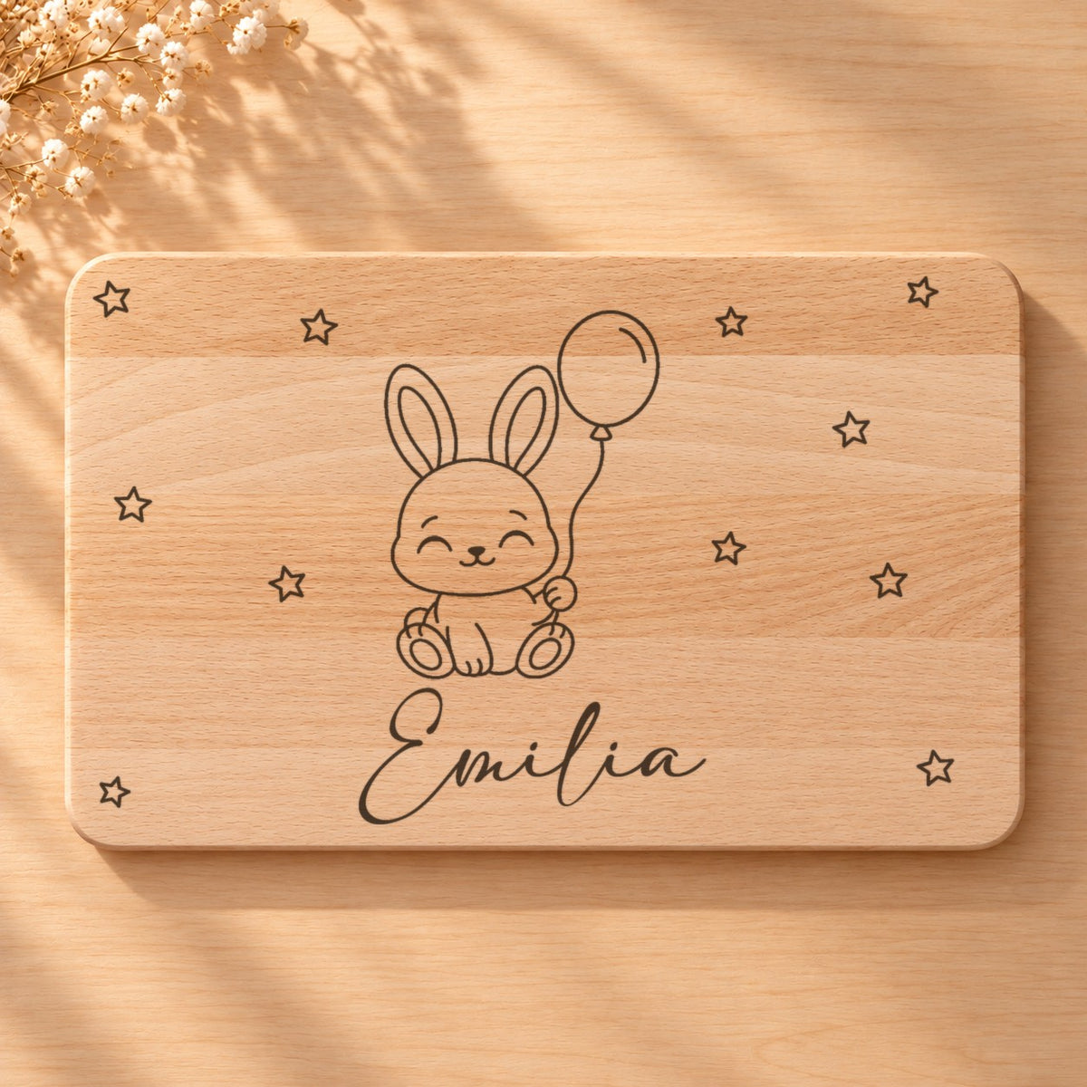 Nahaufnahme der Lasergravur: Hase mit Luftballon und der Name Emilia in Schreibschrift auf hellem Holz
