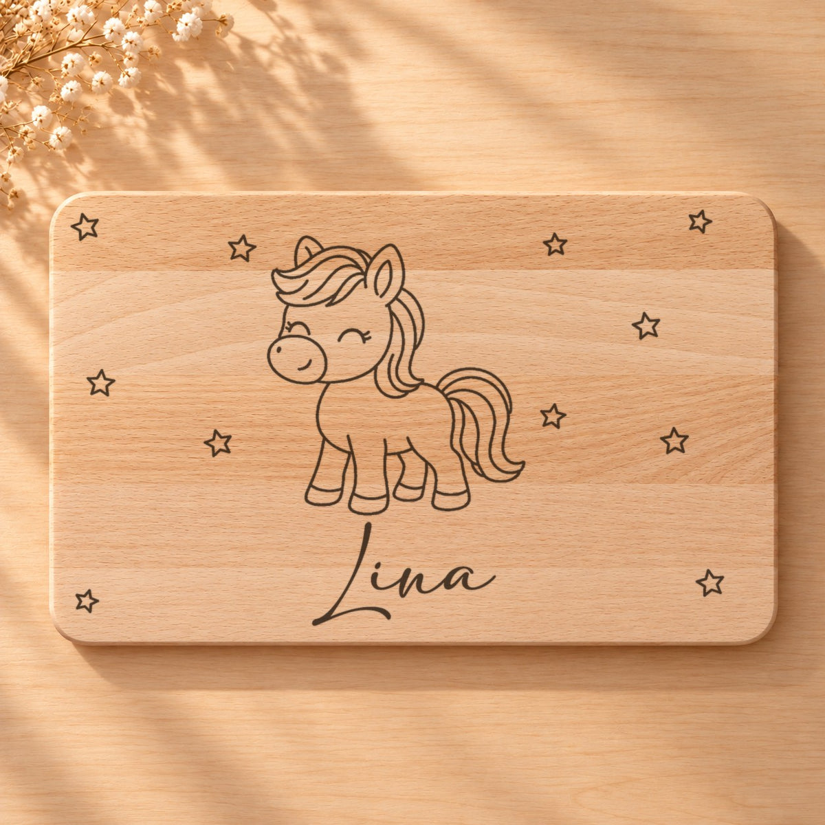 Nahaufnahme der Lasergravur: Pony und der Name Lina in Schreibschrift auf hellem Holz