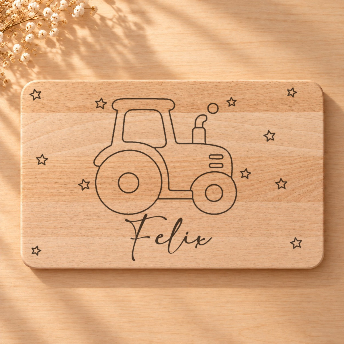 Nahaufnahme der Lasergravur: Traktor und der Name Felix in Schreibschrift auf hellem Holz