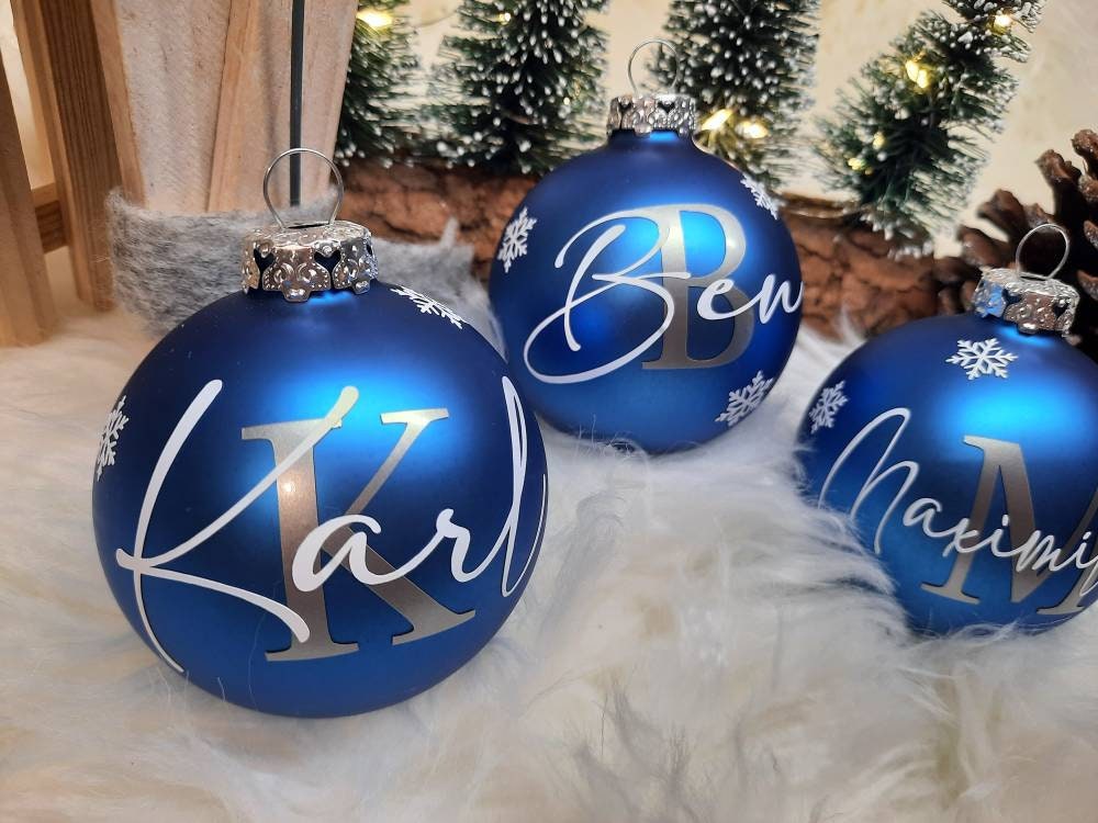 Drei personalisierte blaue Weihnachtskugeln mit Namen Karl, Ben und Maemi sowie Schneeflocken