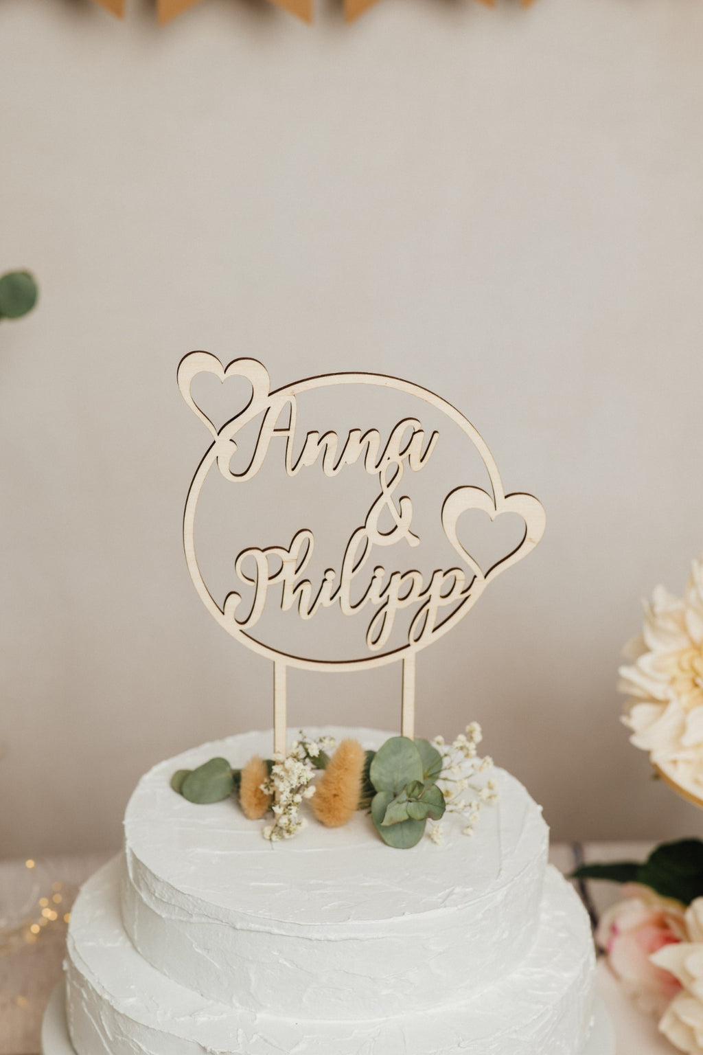Runder Caketopper zur Hochzeit aus Holz mit den Namen Anna & Philipp auf einer Hochzeitstorte