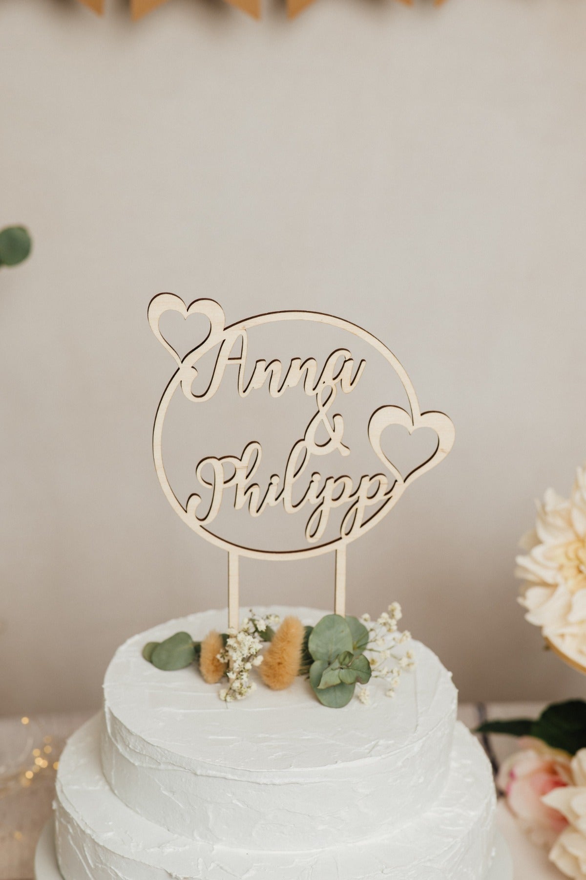 Runder Caketopper zur Hochzeit aus Holz mit den Namen Anna & Philipp auf einer Hochzeitstorte