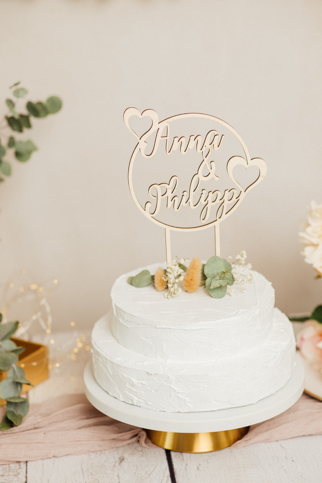 Runder Caketopper zur Hochzeit auf einer Torte auf goldenem Tortenständer