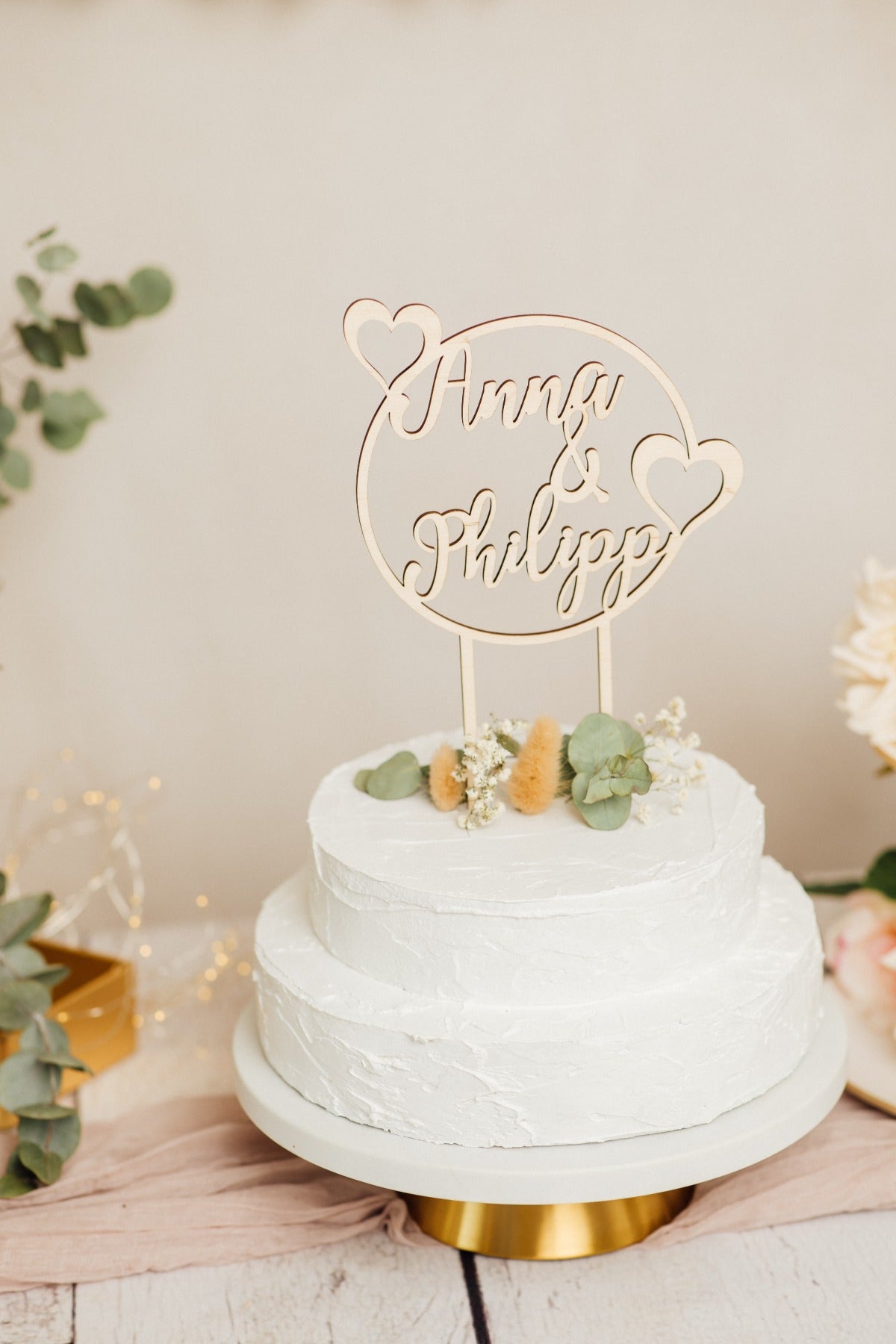 Runder Caketopper zur Hochzeit auf einer Torte auf goldenem Tortenständer