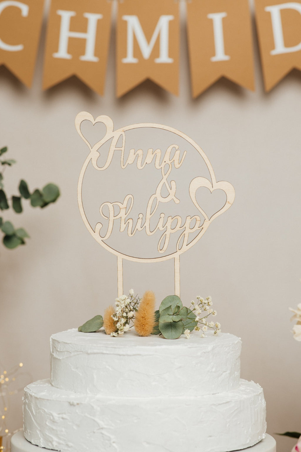 Runder Caketopper zur Hochzeit mit Namen vor einer Wimpelkette