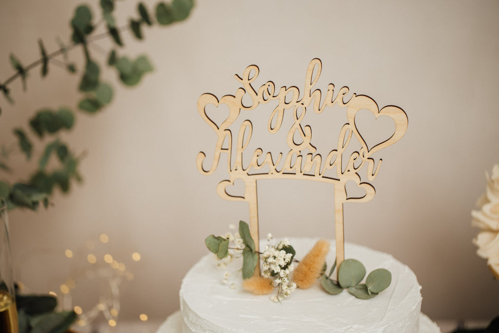 Personalisierter Caketopper mit Namen und Herzen auf einer Hochzeitstorte