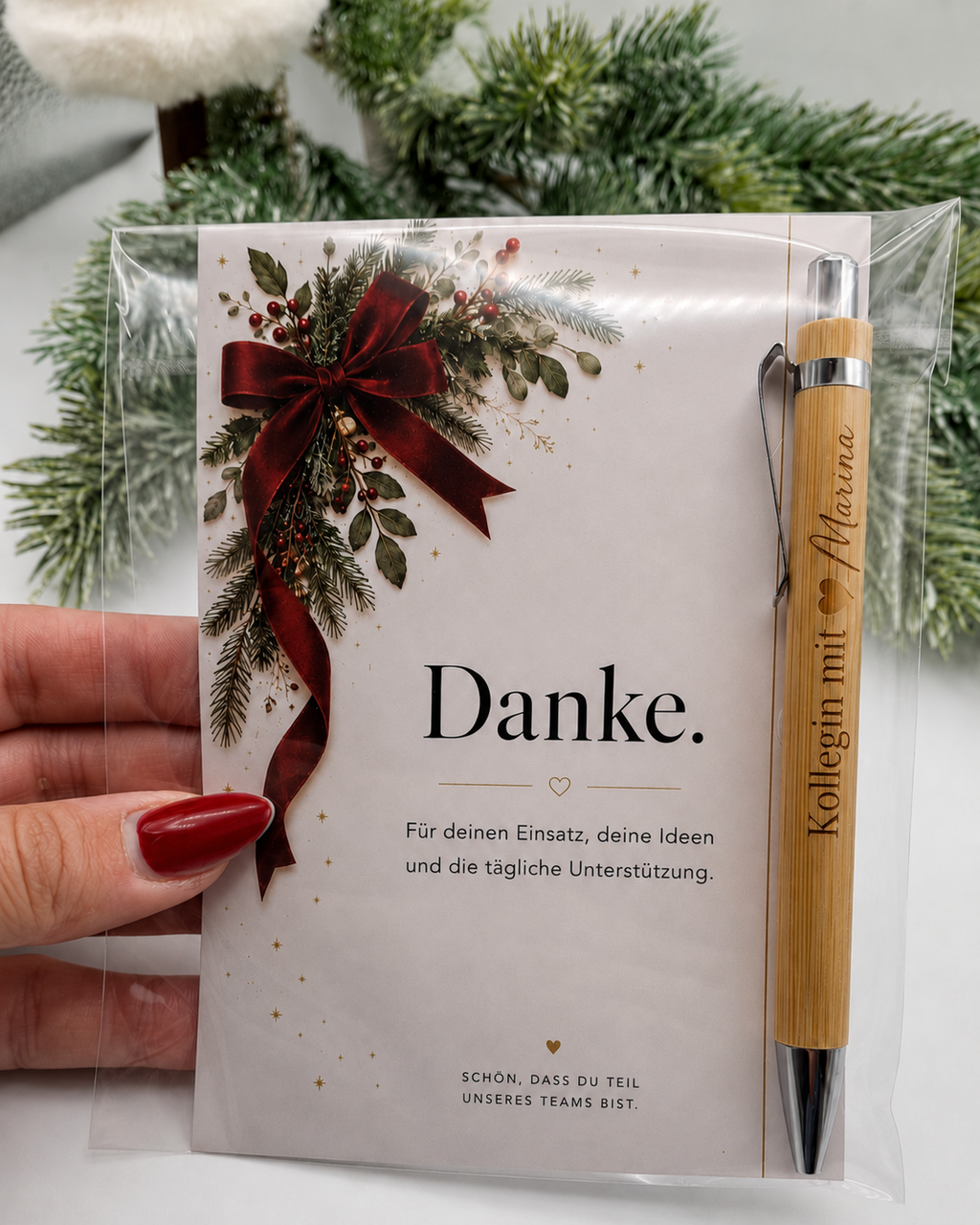 Weihnachtskarte „Danke.“ mit personalisiertem Kugelschreiber in der Hand gehalten